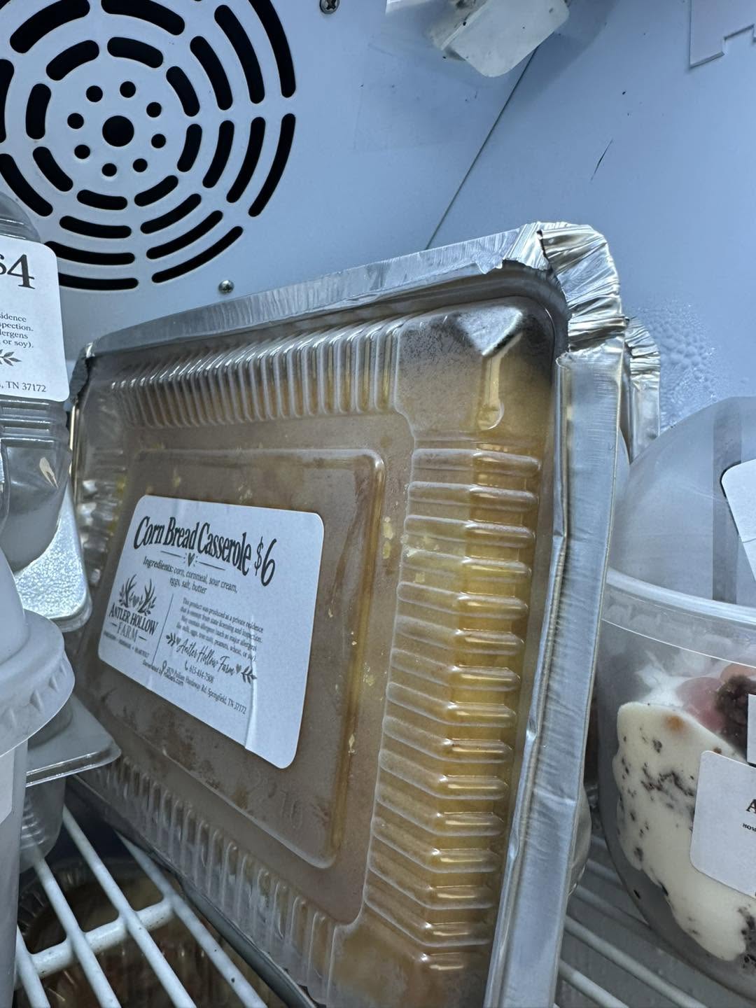 A labeled tray of Antler Hollow Farm cornbread casserole in the stand's refrigerator.
